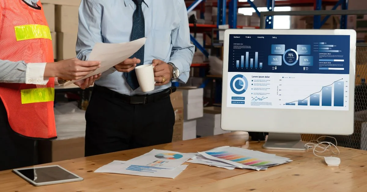 Workers reviewing analytics dashboard in warehouse office.